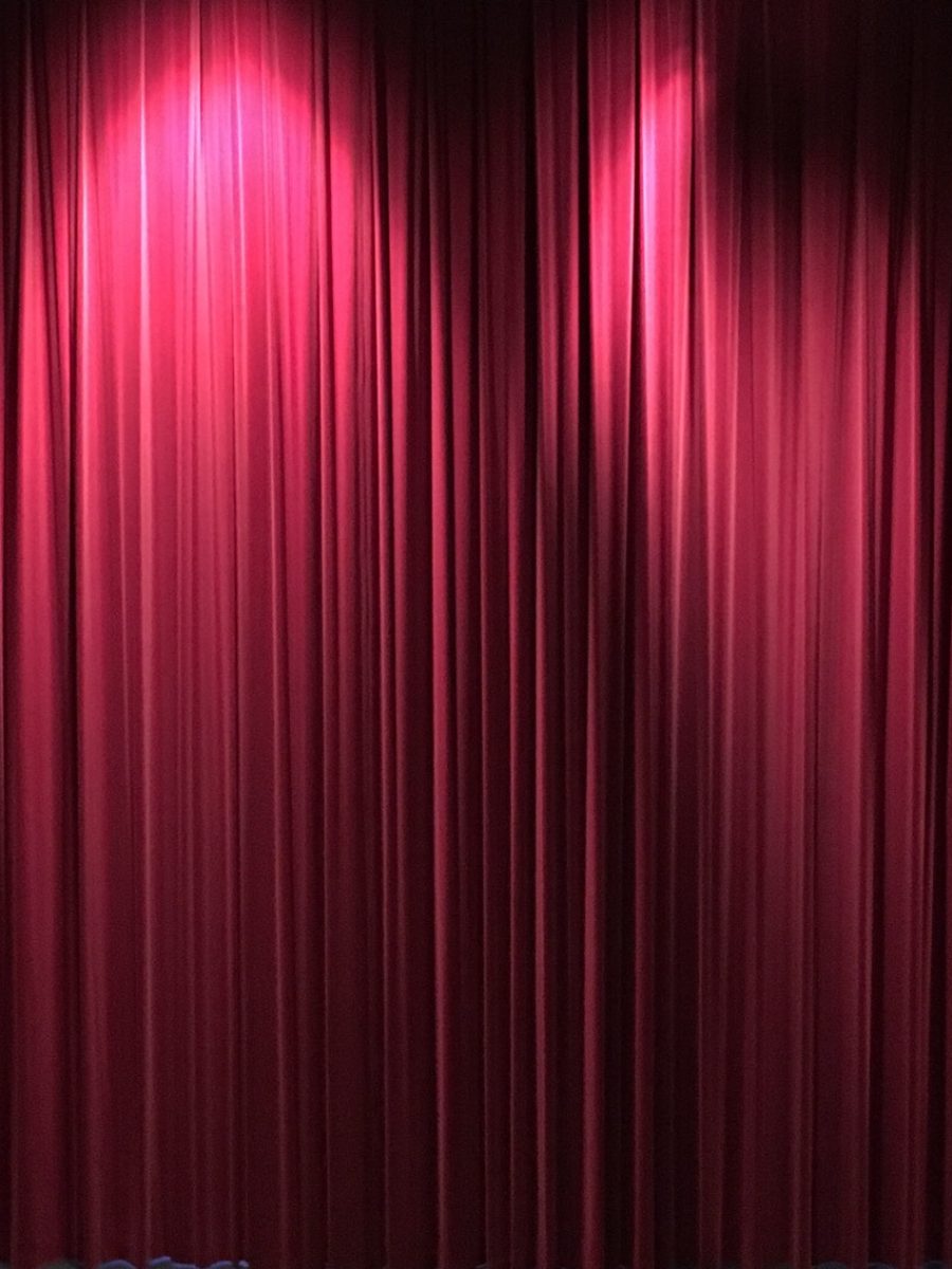 closed-red-theater-curtains-on-stage-with-lights-from-above-partially-lighting-the-curtains.jpg